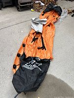 Full view of deflated orange and black inflatable boat with visible black seat.