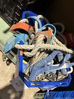 Lot of industrial strength ropes and fasteners bundled together showing wear and dirt, stored in blue crate