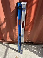 Two levels propped against a surface, one blue and one silver, approximately 4 feet long each.