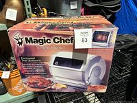 The Magic Chef horizontal twin rotisserie oven box showing branding, product image, and features.