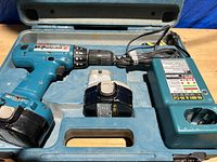 Makita cordless drill, rechargeable battery, and charger inside carry case.