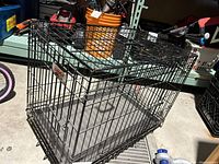 Photo of the black folding metal pet crate showing the side and top structure with plastic bottom.