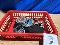 Red plastic basket with assorted used circular saw blades, hole saws, metal accessories