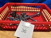 Red plastic basket containing assorted chrome sockets and one ratchet handle.