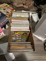 Top view of cardboard box filled with comic books including an X-Force issue visible on top