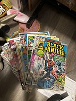 A photo showing a stack of seven Silver and Bronze Age Marvel comic books with the top comic featuring Black Panther on the cover.