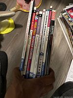 Spine view of a collection of comics including multiple Wonder Woman volumes and an Elektra comic.
