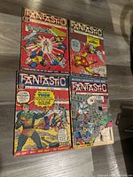 Four vintage Fantastic comic magazines laid out on a wooden floor. Each cover features different Marvel characters including Iron Man and Thor. Covers are colorful with minor visible wear.