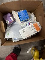 Top view of a cardboard box containing multiple medical sponges and bandage products in their original packaging.
