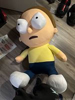 Full body shot of large Morty plushie lying on floor showing front details and colors.