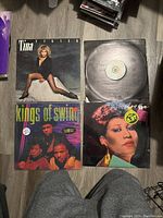 Photo of four vinyl record albums: Tina Turner 'Private Dancer', Kings of Swing, Aretha Franklin and one with partially visible label, laid flat showing covers