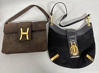 Photo showing two vintage fashion designer handbags from Italy side by side, one brown suede with a gold H clasp, one black suede and leather with gold-tone hardware and clasp.