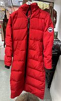 Front view of full-length red parka on display stand