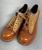 Front and angled view showing leather toe caps, laces, and fabric panels of the oxford shoes.