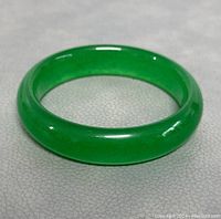 Front angle photo showing the vibrant green polished natural jade bangle, highlighting the smooth surface and D-shape design.