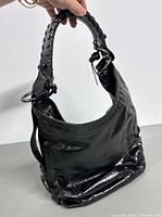 Front side view of vintage black leather shoulder bag showing braided strap and metal hardware.