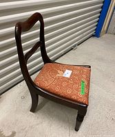 Side view of the antique mahogany low hall chair showing the curved backrest and upholstered seat.