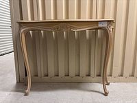 Full view of the wooden side table showing overall shape, curved legs, and natural wood finish.