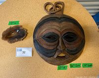 Photo of the vintage round solid wood mask and the mid-century modern agate ashtray side by side on a round table with measurement tags.