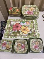 Melamine dinnerware including large rectangular placemats, large square plates, smaller rectangular plates, and small square dishes with tropical hibiscus flower design.