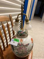 Full view of the mid-century modern ginger jar lamp showing the ceramic base with floral design and three brass light sockets with bulbs.