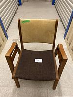 Front view of the MCM boomerang style chair showing oak arms, brown fabric seat, and beige vinyl backrest.