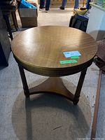 Full view of the round mahogany lamp table showing the tabletop and base with three legs connected by a triangular lower shelf.