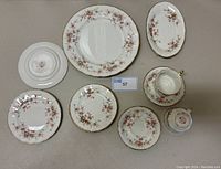 Photo of the entire bone china set laid flat showing all plates, teacups, and saucers with floral and gold detailing.