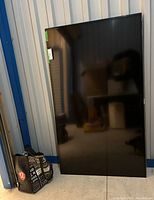 Full front view of Samsung flat screen TV showing black screen and bezel, approximately 60 inches tall.