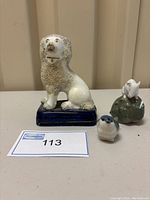Front view of the trio: Staffordshire dog seated on blue base, two porcelain mice (Royal Copenhagen and Lomonosov) in front and on green base.