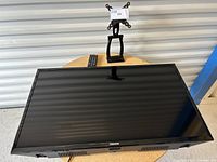 Front view of Toshiba 32-inch TV showing screen, stand, and remote on a table surface.