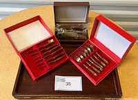 Overall view of all cutlery sets in red boxes on the wood tray