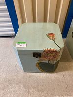 Front view of vintage hinged cube coffee table with lotus flower design and latch.