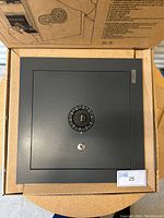 New Steal-Safe wall safe in original box, front view showing combination dial and key lock.
