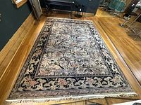 Full view of rectangular rug on hardwood floor showing overall pattern, border and fringe.