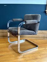Side view showing chrome cantilever frame with padded armrests and sage green suede upholstery, light pitting visible on metal
