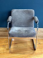 Front view of the cantilever armchair showing padded seat, backrest, and armrests covered in sage suede upholstery.