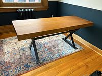 Angled view showing wood tabletop and steel X-frame legs