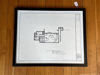 Full view of framed blueprint laid on hardwood floor