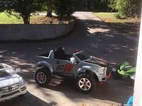 Side view of a silver kid's ride-on F150-style jeep with large wheels and '60' decals.