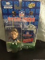 Front view of Kerry Collins NFL Headliners bobblehead figurine in original sealed packaging showing figure, packaging graphics, and included collector catalog.