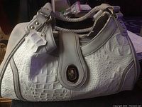 White Marc Chantal ladies purse showing front with toggle closure and textured crocodile pattern.