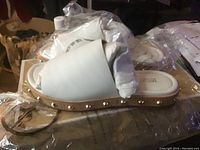 Side view of single white Michael Kors slide sandal showing studded sole trim and overall design