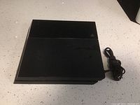 Top-down view of the black PlayStation 4 console placed on a light-colored speckled countertop.