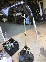 Full unit showing adjustable metal pole, black triangular steam head with fabric hanger attachment, flexible steam hose, and black base unit on floor.
