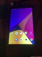 Tablet turned on showing home screen with colorful wallpaper and app icons.