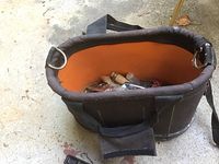 Top view of black and orange fabric tool bag showing wooden handles and various tools inside