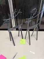 Two black metal reindeer figurines standing side by side on a table, facing different angles. Both have angular legs and branded #31 tag.