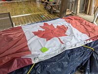 One Canadian flag spread out partially on a table, showing red maple leaf and red side bars.