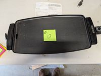 Top view of the Black & Decker electric grill showing the flat cooking surface with side handles and power cord.